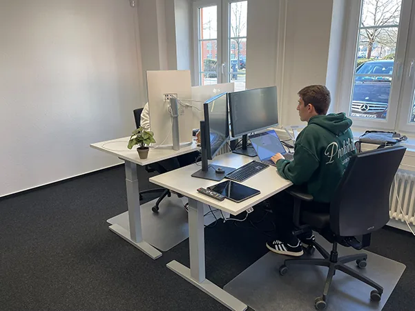 Entwickler am höhenverstellbaren Doppel-Monitor-Arbeitsplatz
